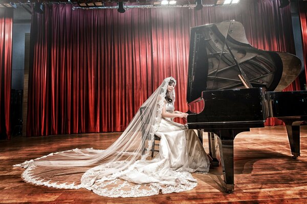 Fille asiatique en robe de mariée et voile joue du piano