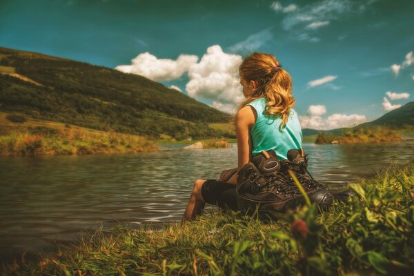 The girl sitting on the shore looks into the distance