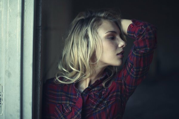 Ragazza bionda in camicia a scacchi con la mano sollevata