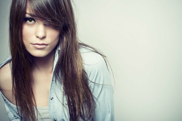 A girl with long black hair in a T-shirt and shirt on a monochrome background