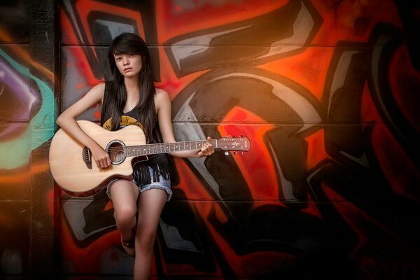 Chica guitarrista en el fondo de graffiti