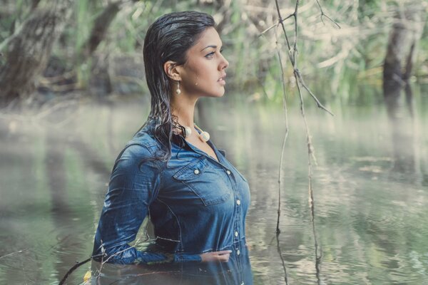 Fille dans une robe bleue se tient à la taille dans l eau