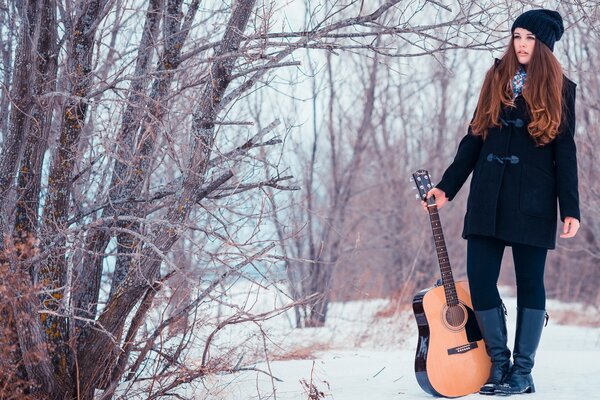 Chica con guitarra en el bosque de invierno