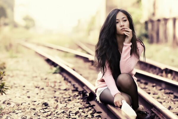 Sad girl sitting on the rails