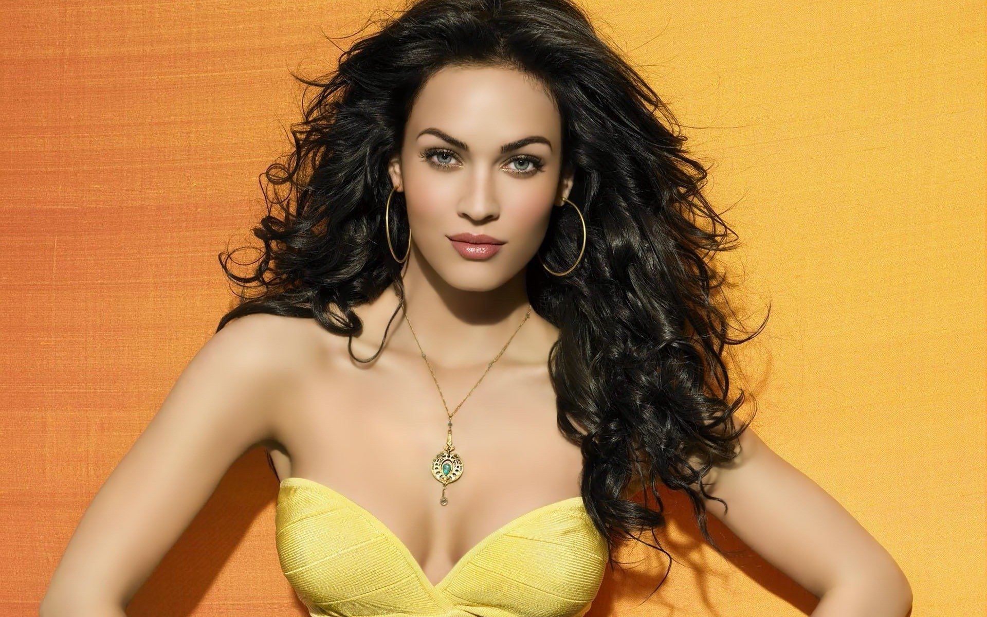 megan fox dziewczyna modelka aktorka twarz spojrzenie włosy loki wisiorek biżuteria kolczyki tło