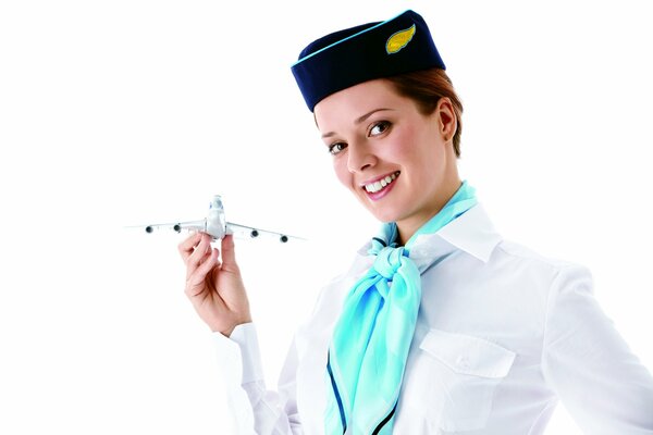 A smiling flight attendant holds an airplane in her hand