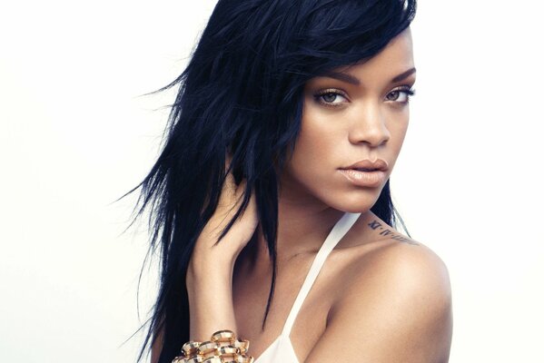 Rihanna at a photo shoot with her hair down and a tattoo on her shoulder