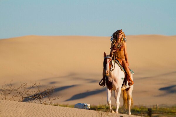 Cavboika a cavallo nel deserto con un cane