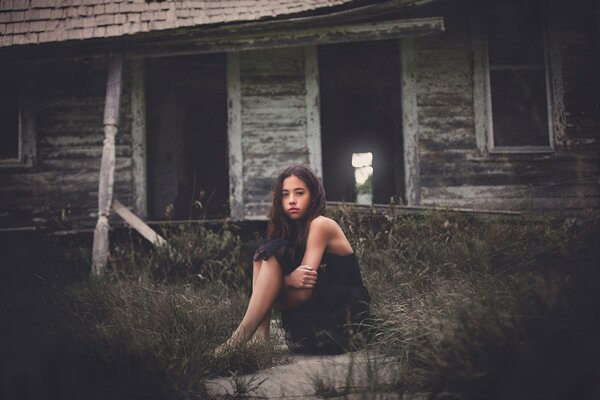 A lonely girl on the background of an old house