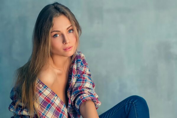 Portrait of a long-haired girl in a plaid shirt and jeans