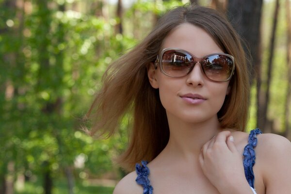 A girl with glasses walks through the forest