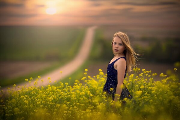 Niña en el campo junto a la carretera al atardecer