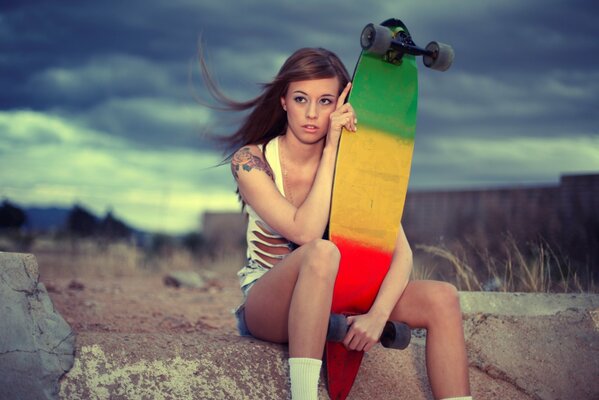 A girl is sitting with a skateboard in her hands