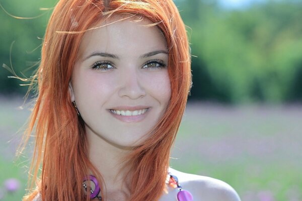 Red-haired girl in nature with a smile