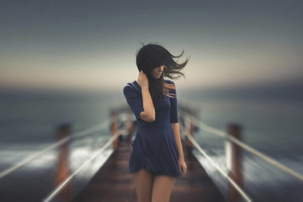 Chica en el muelle, en el viento, pelo suelto