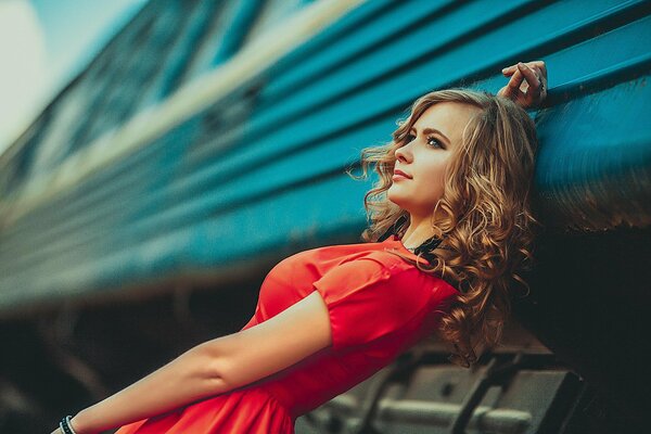 La composición de una chica con un vestido rojo en el fondo de un tren