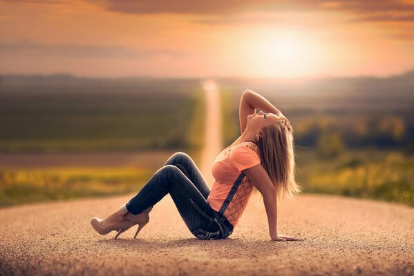 Ragazza seduta sulla strada al tramonto