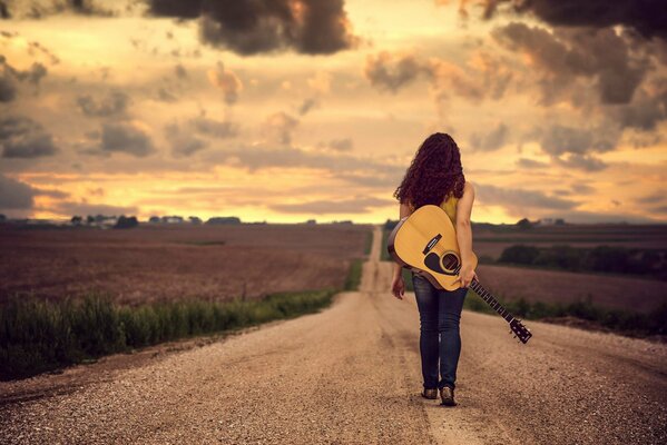 Mädchen, das mit einer Gitarre frei auf der Straße schreitet