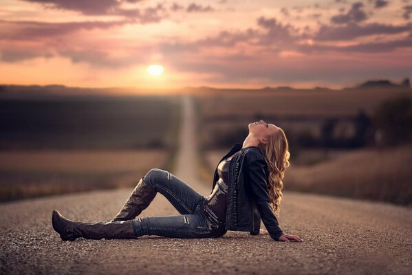 A girl in a denim suit is lying on the road