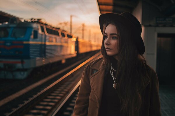 Ragazza con cappello nero alla stazione ferroviaria