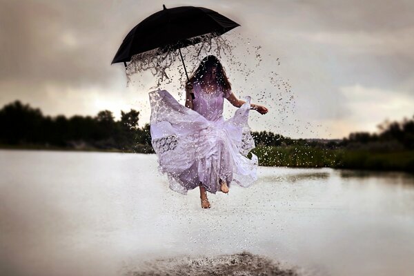 Fille sous le parapluie saute sur les flaques d eau