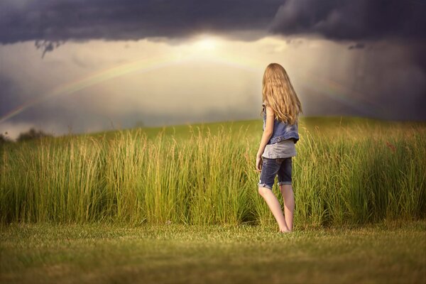 A girl in a field looks at the gray sky