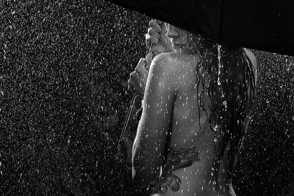 Fille nue de l arrière sous la pluie sous un parapluie noir avec les cheveux lâches et un tatouage sur le côté gauche de la photo en noir et blanc