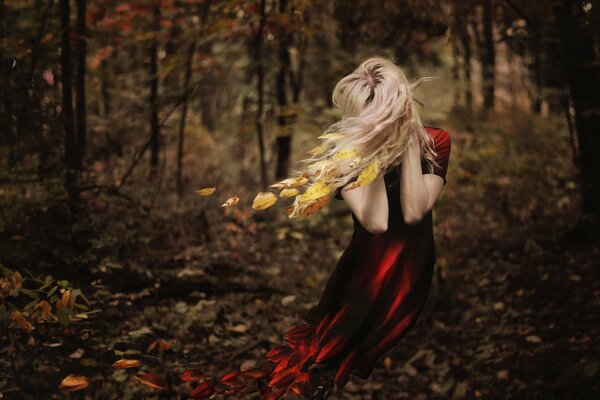 Chica en vestido rojo en otoño en el bosque