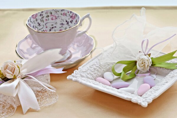 Вкусный натюрморт с чайной чашкой, цветами и конфетами