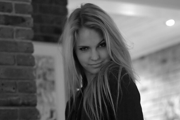 Black and white photo of model Emily Marie. In the photo, the girl sweetly squinted her eyes