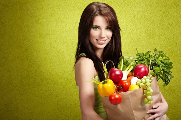 Девушка с пакетом овощей на салатовом