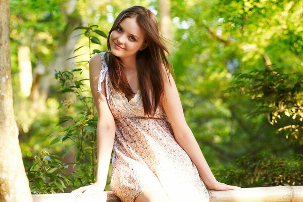 Beautiful girl on a log in a dress