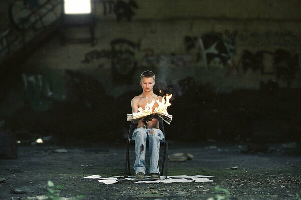 Mec assis sur une chaise avec un journal brûlant