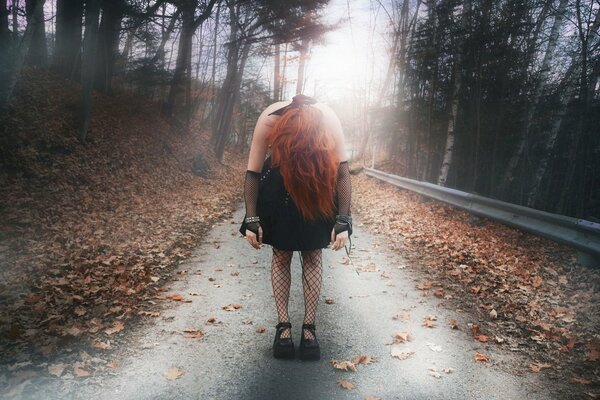 Pelirroja chica en el camino en otoño