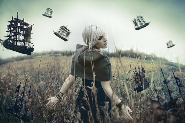 A girl walks through a field next to flying ships