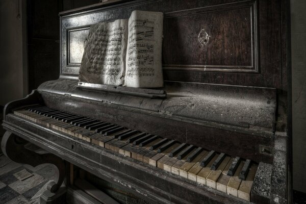 Stary, zgrzybiały fortepian, na którym stoją te same stare nuty