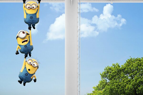 Three minions hang against the blue sky