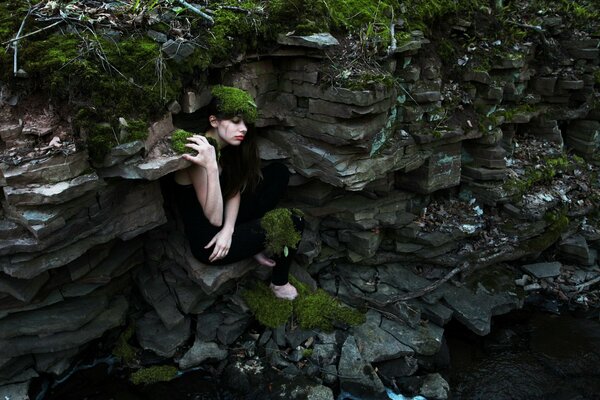 The girl on the ledge of the cliff is covered with moss