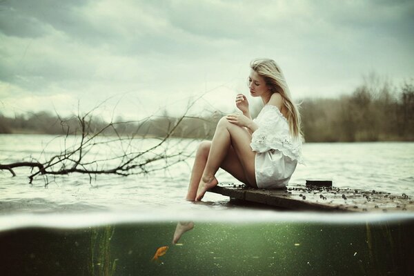 Sad girl near the water. Autumn depression. Girl and goldfish