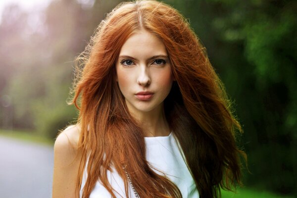 Piękna dziewczyna z rudymi włosami obok lasu