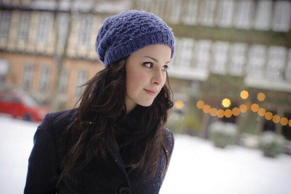 Brune dans un chapeau violet et un manteau violet se dresse sur le fond de la ville d hiver avec des lumières de Noël