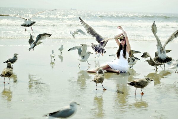 A girl by the sea is photographed with birds