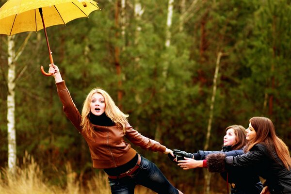 Three girls with an umbrella in autumn