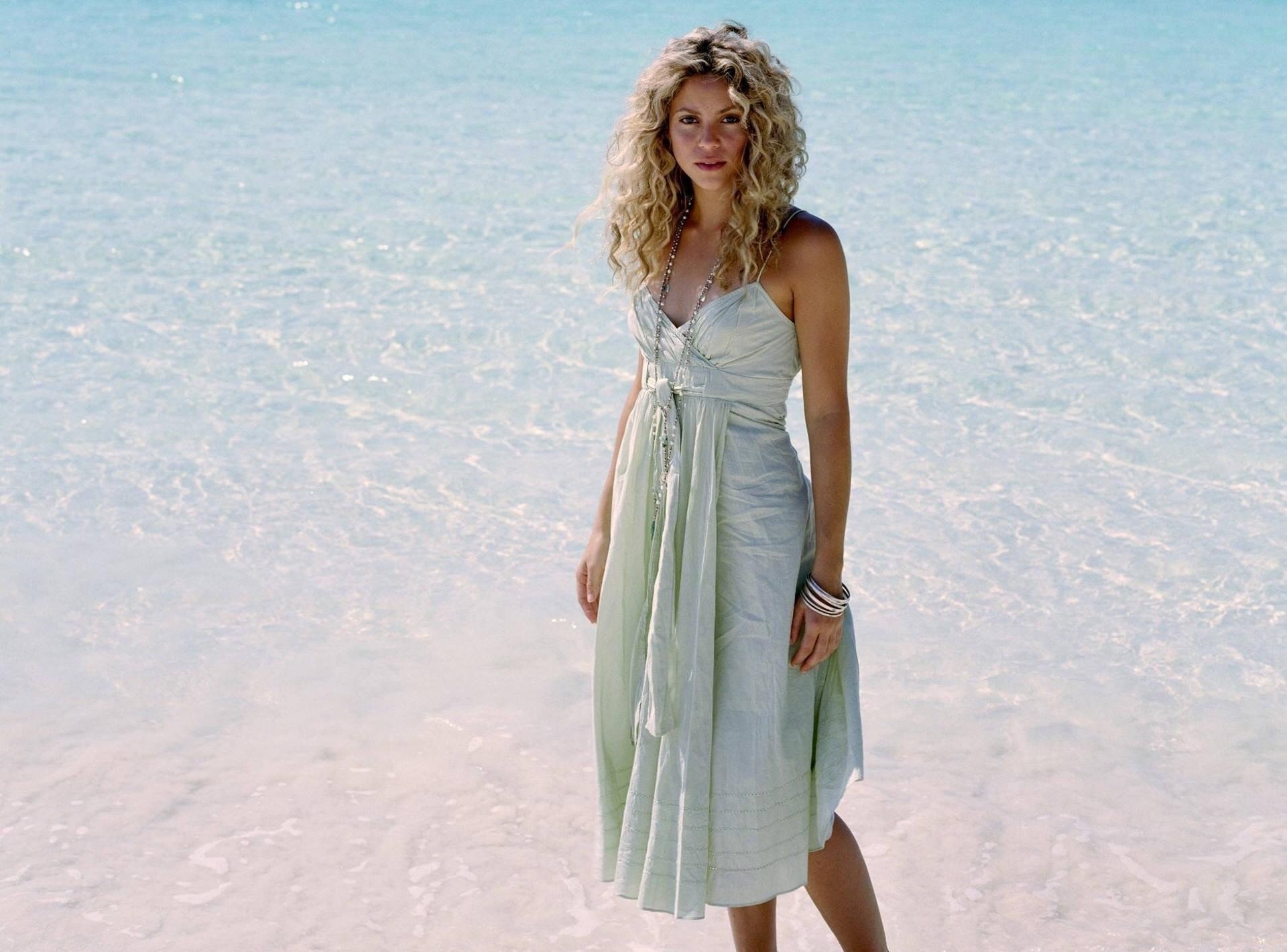 musique chanteuse shakira fille blonde cheveux boucles bleu clair été robe perles bracelets plage eau mer