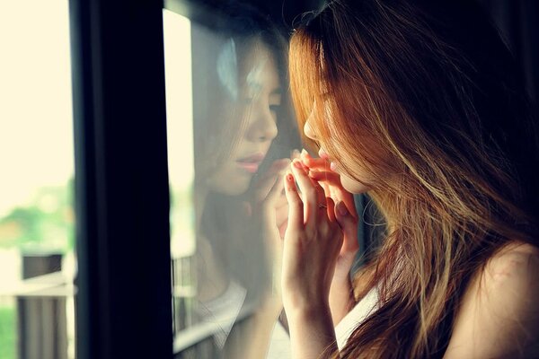 A beautiful girl is standing at the window