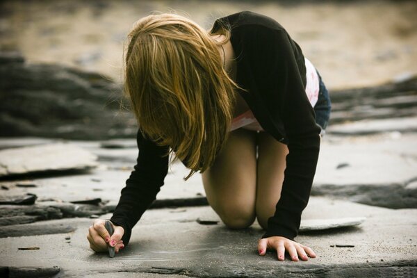 Gloomy photo of a girl writing on the asphalt