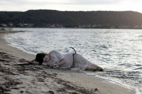 Una niña yace en la arena junto al mar