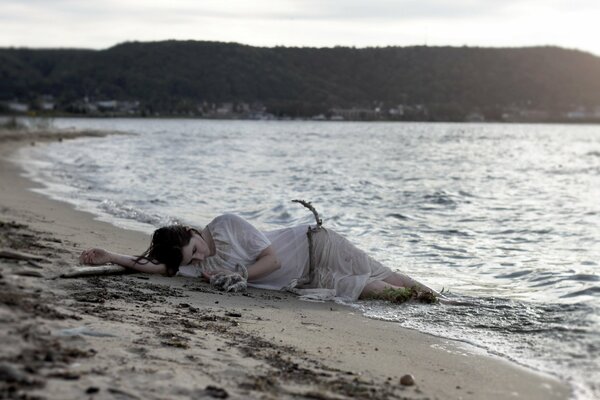 Fille se trouve sur le sable au bord de la mer