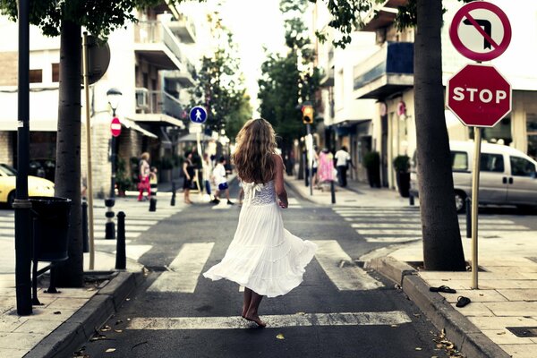 Девушка в белом платье гуляет по городу