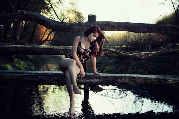 Dziewczyna w kostiumie kąpielowym siedzi na moście